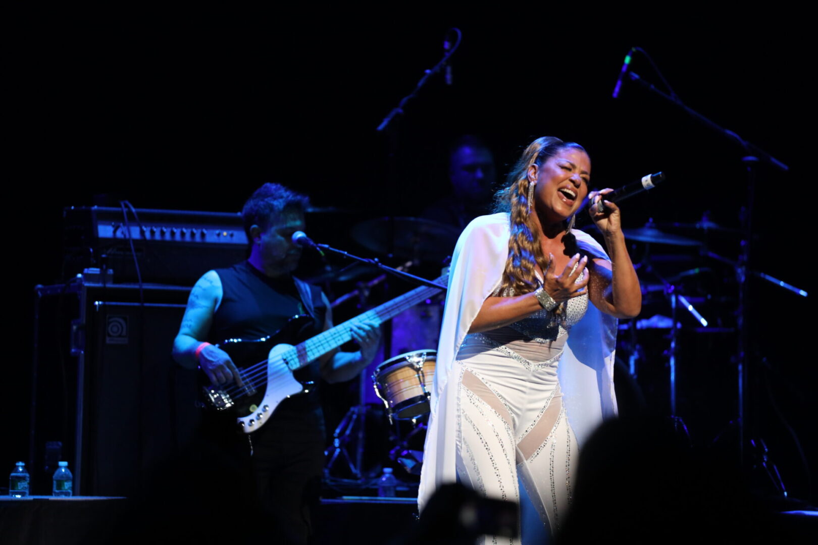 A woman singing into a microphone on stage.