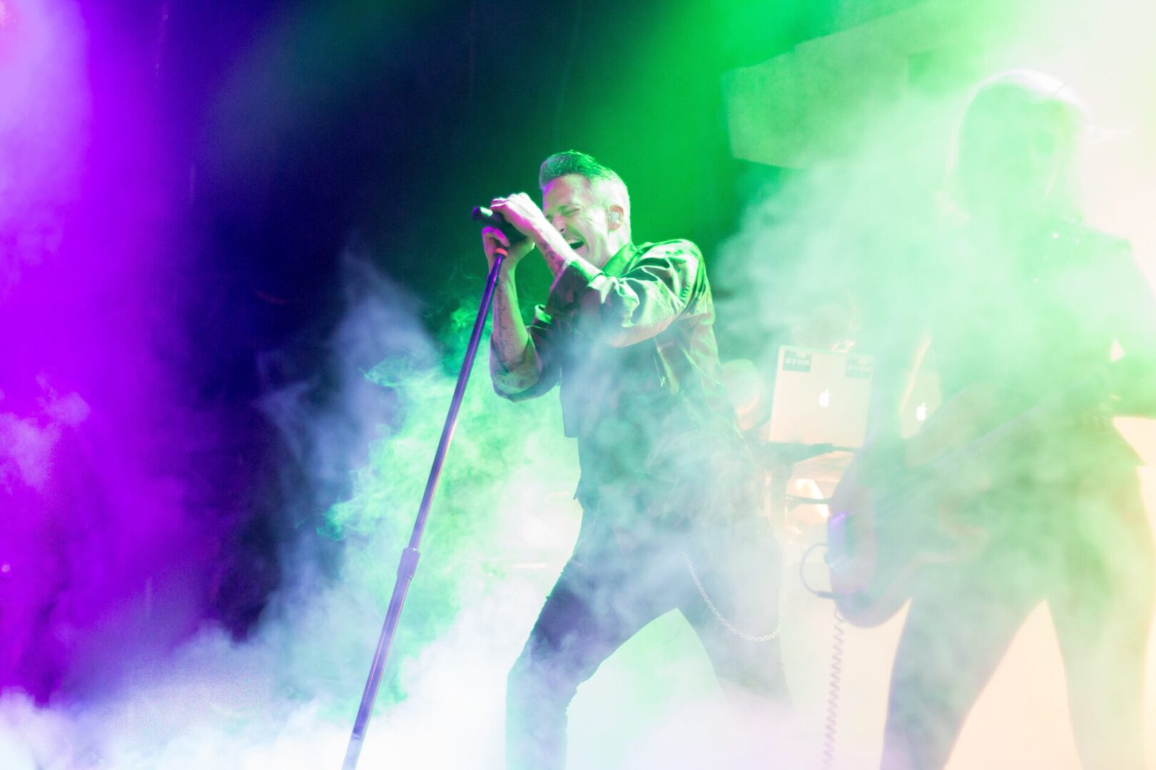 A man holding a microphone in front of green smoke.