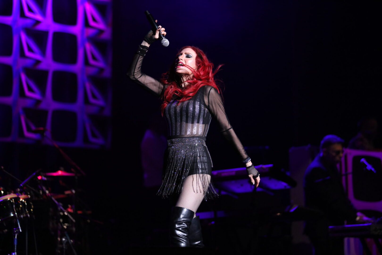 A woman with red hair and black outfit on stage.