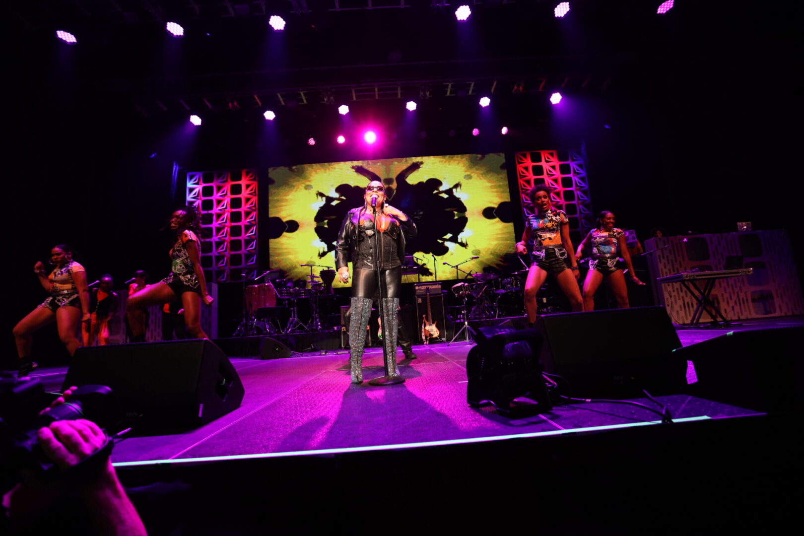 A man standing on stage with several dancers behind him.