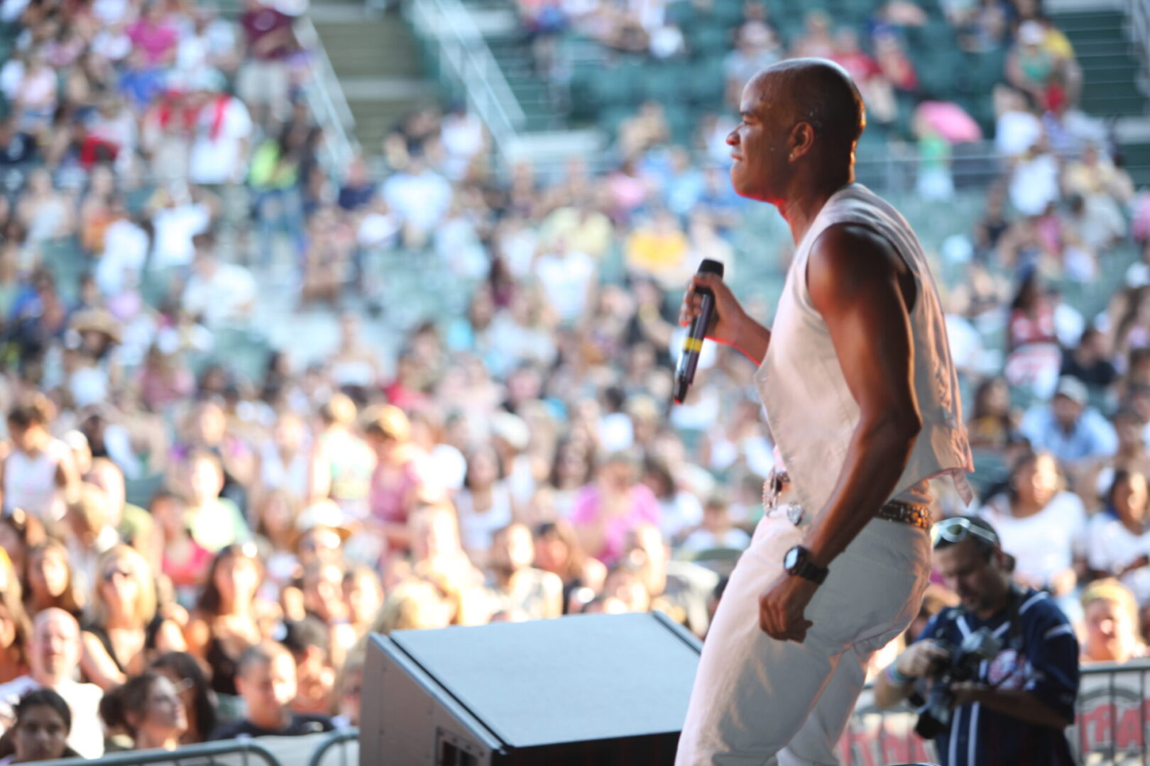 A man is holding a microphone while standing in front of an audience.