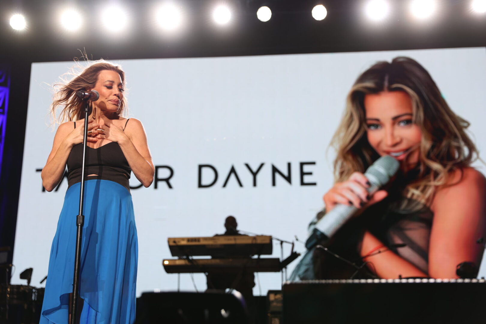 A woman singing on stage with a microphone.