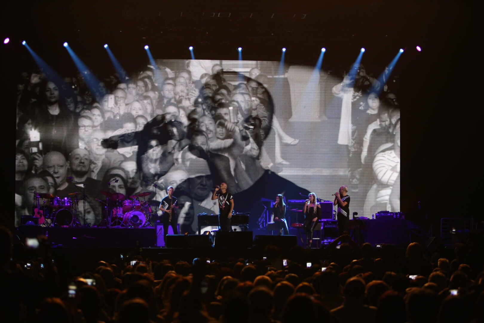 A large screen showing a concert with people on it