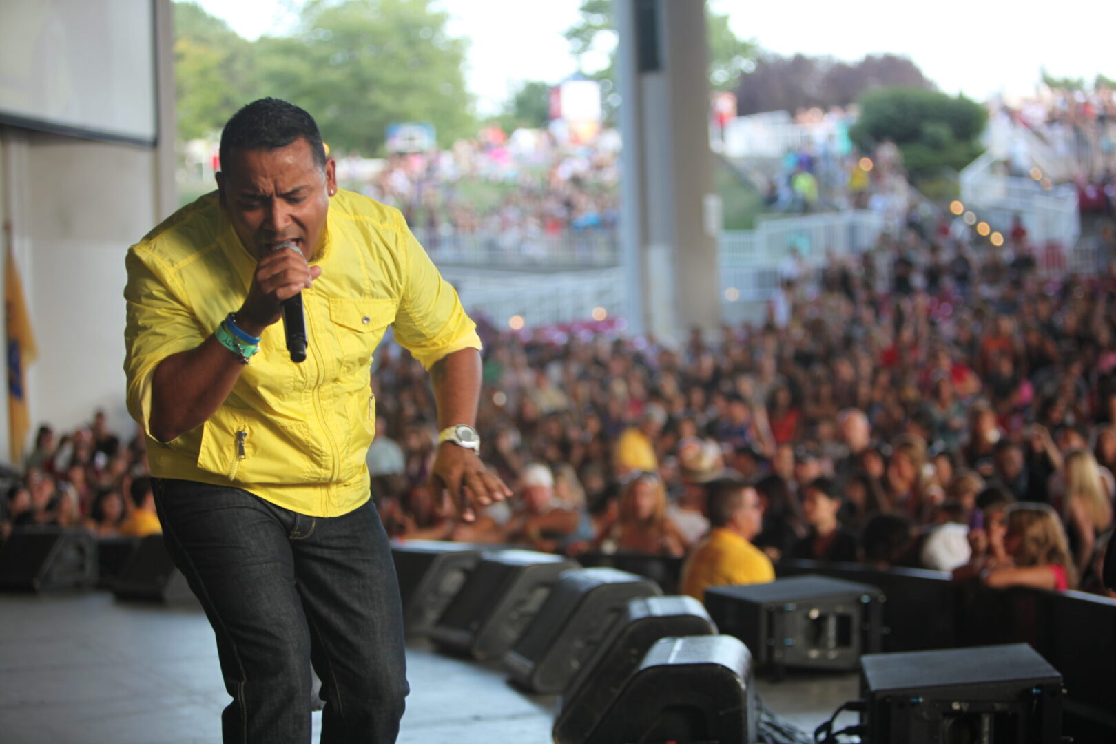 A man in yellow shirt singing on stage.