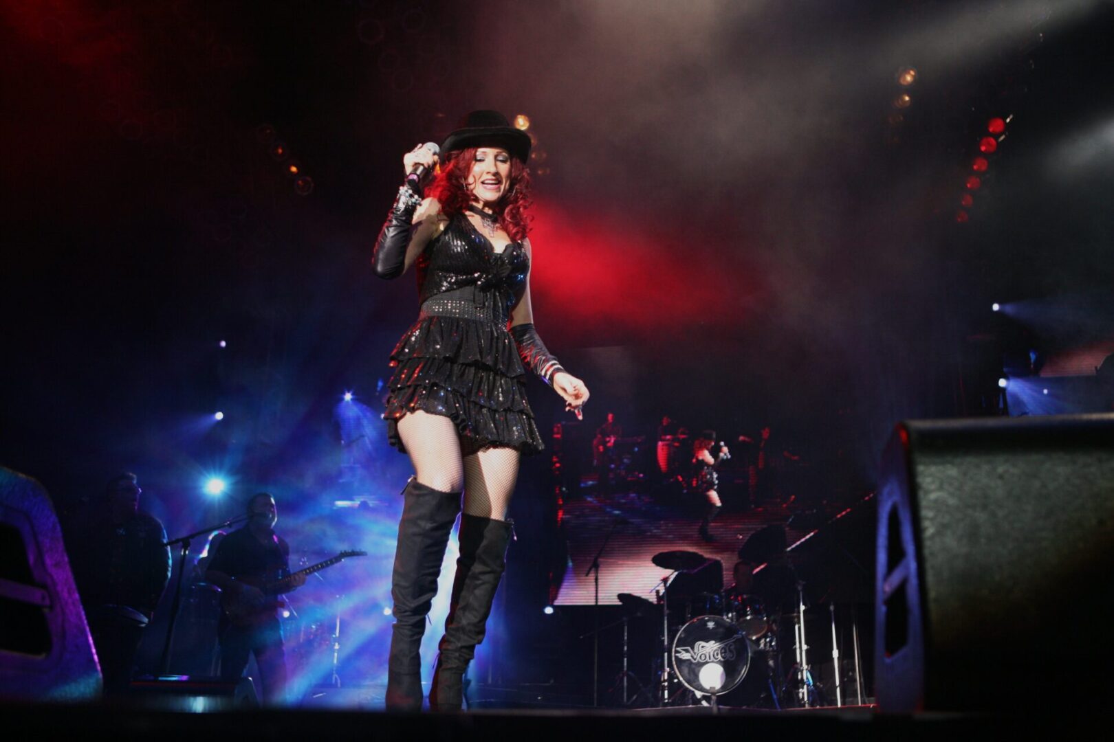 A woman in black dress and boots holding a microphone.