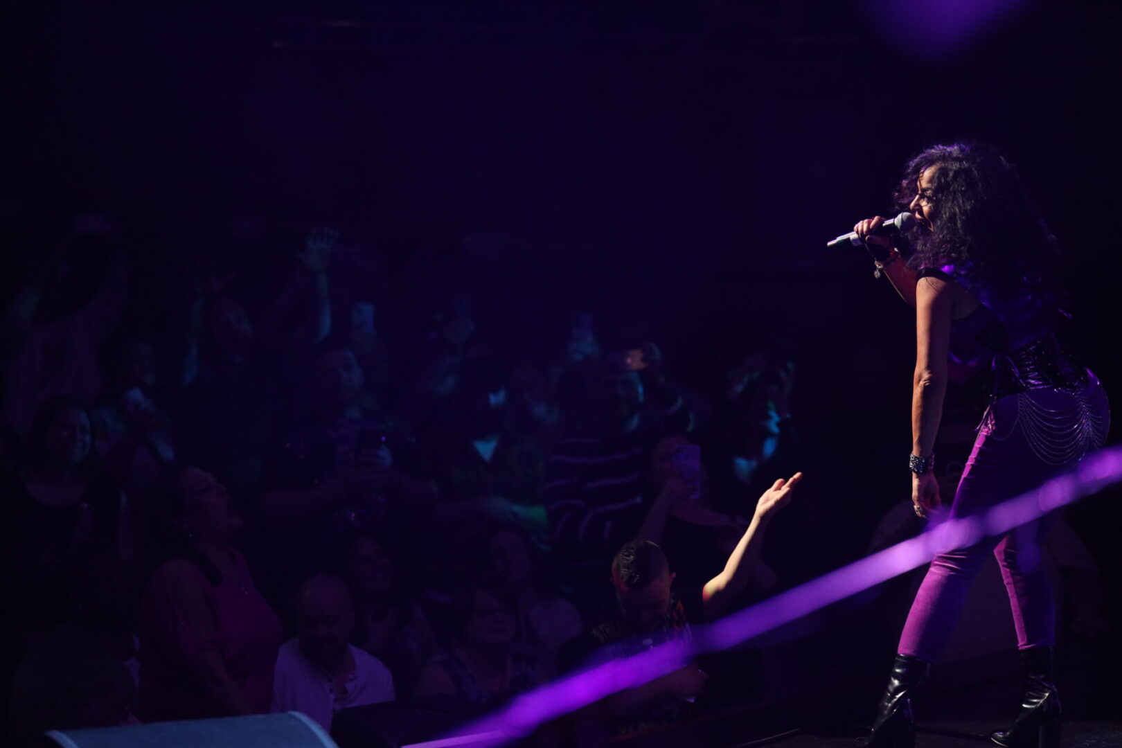 A person singing on stage with purple lights