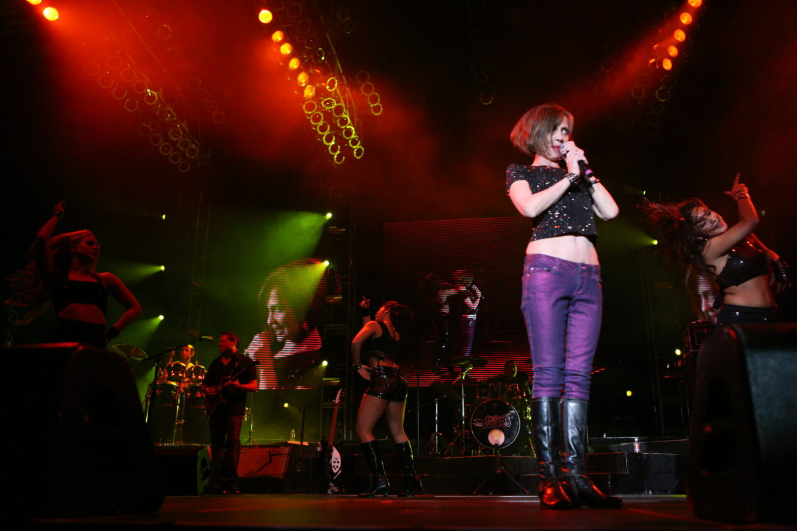 A woman singing on stage with other people in the background.