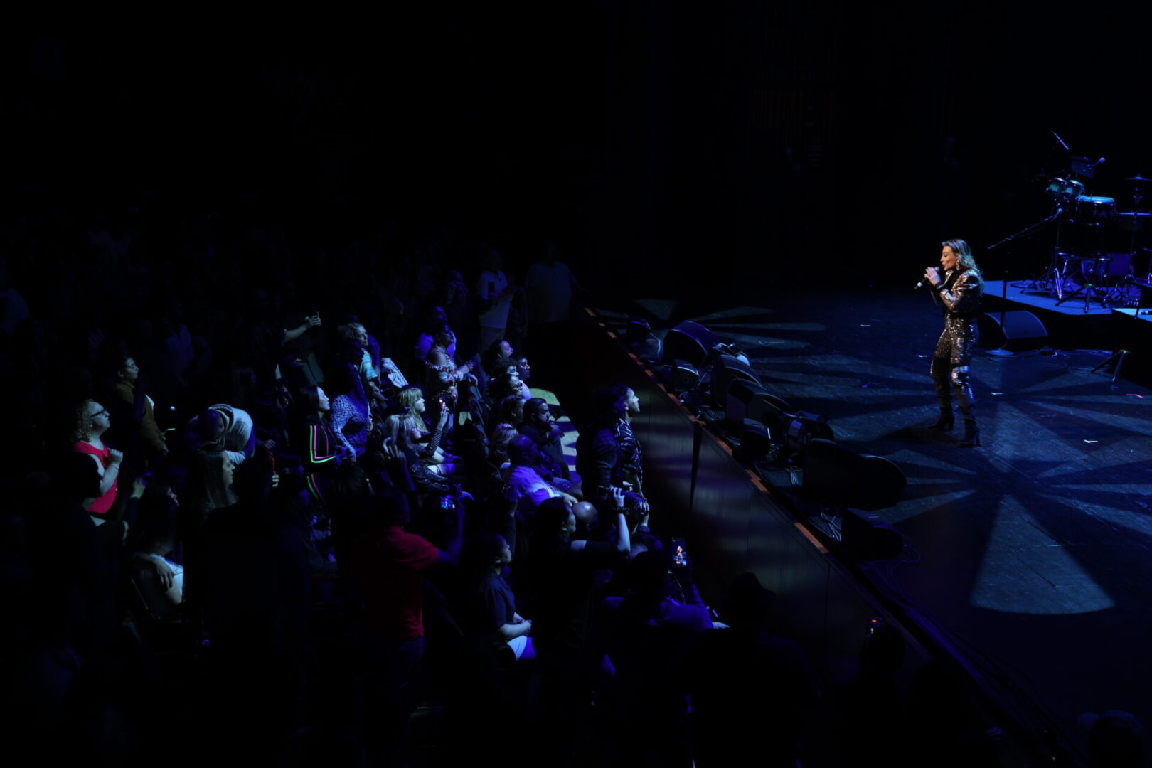 A group of people sitting on the ground in front of a stage.