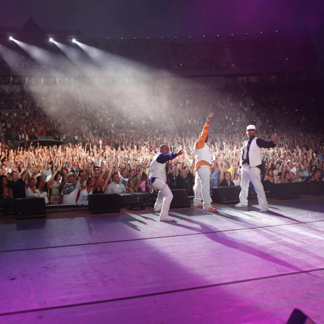 A group of people on stage with a crowd in the background.