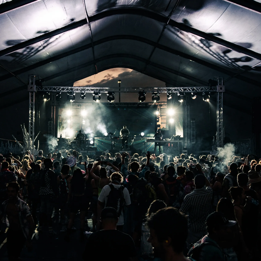 A crowd of people in front of an outdoor stage.