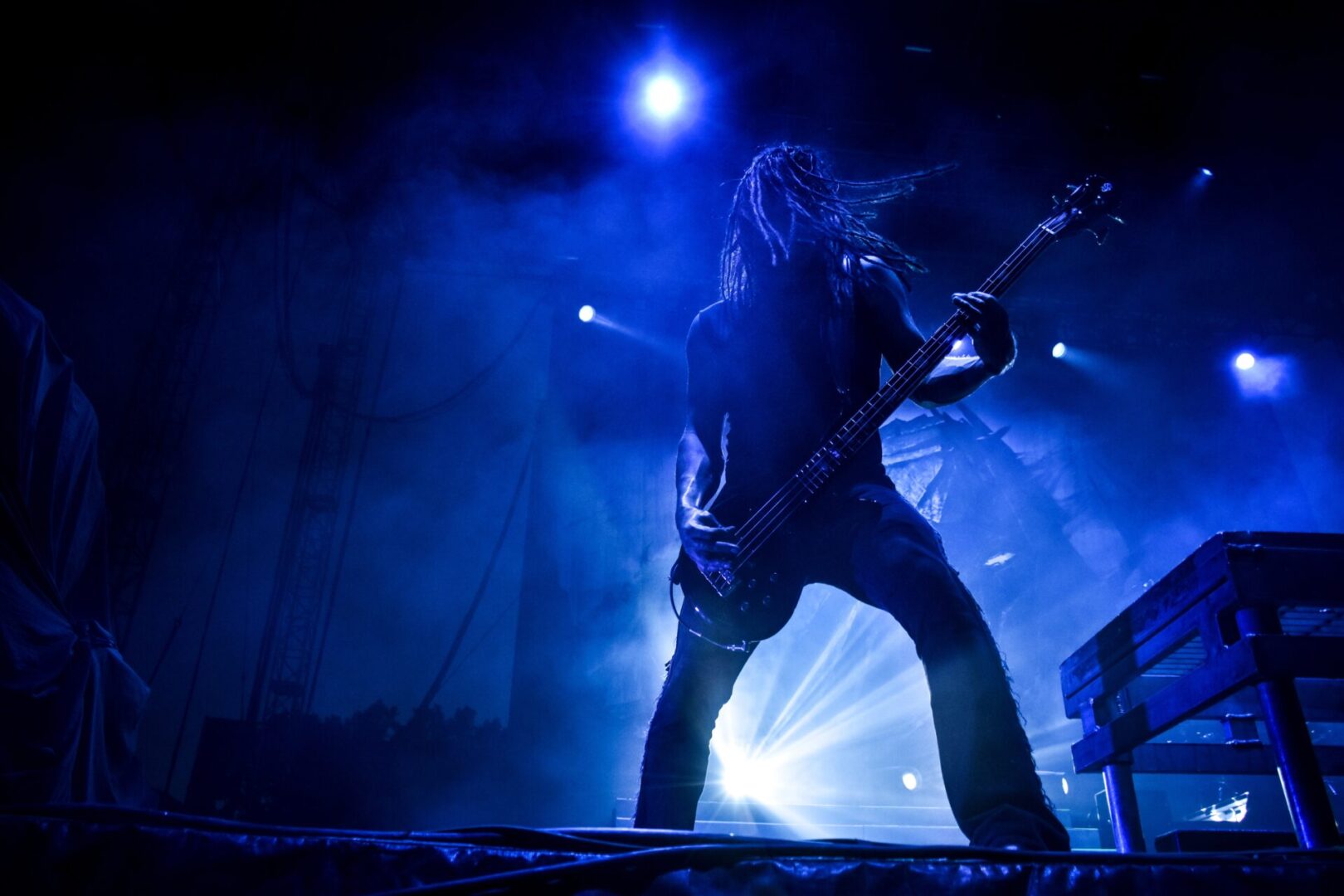 A man with long hair is playing guitar on stage